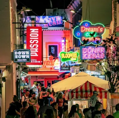a crowd of people walking down a street with neon signs at Albufeira Central Apartment, 10 mins walk to beach in Albufeira