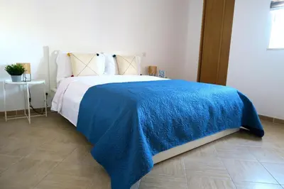 a bedroom with a blue blanket on a bed at Albufeira Central Apartment, 10 mins walk to beach in Albufeira