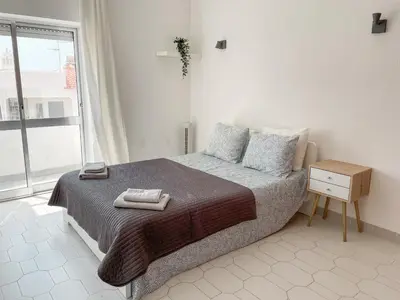 a white bedroom with a bed and a window at Sunny House Albufeira in Albufeira