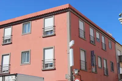 a red building with white windows on a street at Dom Fernando I in Loulé