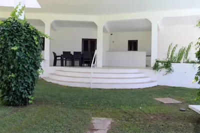 a white house with stairs and a table and chairs at Villa Hibiscus, great location in Vilamoura, lush green lawns and garden in Quarteira