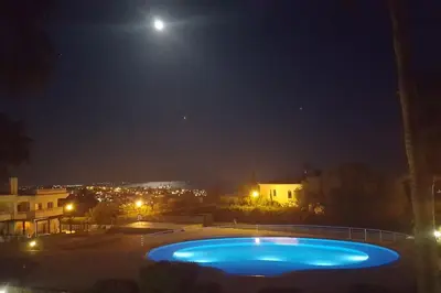 a large blue swimming pool at night with the moon at Casa Felicidade in Albufeira