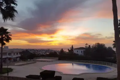 a swimming pool with a sunset in the background at Casa Felicidade in Albufeira