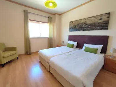 a bedroom with a large white bed and a chair at Casa Felicidade in Albufeira