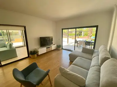 a living room with a couch and chairs and a television at Janelas do Oceano - Casa de Ferias T3 Vilamoura in Vilamoura
