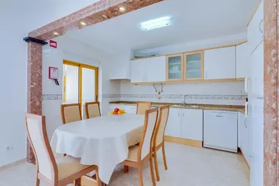 a dining room with a table and chairs and a balcony at AL - Apartamento Atlântida Mar in Quarteira