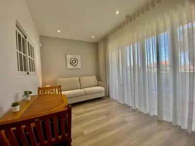 a living room with a couch and a large window at Fresh and cosy appt with Pool, Fiber, LargeTV, Gaming Room in Albufeira