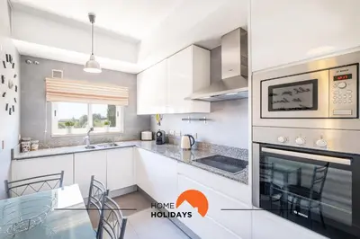 a kitchen with white cabinets and a glass table at #092 Quinta dos Figos by Home Holidays in Albufeira
