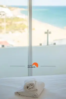 a white towel sitting on a bed in front of a window at #086 Fish House by Home Holidays in Albufeira