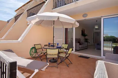 a patio with a table and an umbrella at Albufeira Townhouse beach in Albufeira