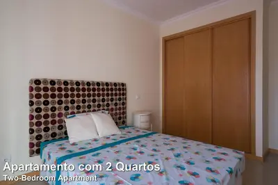 a bedroom with a bed and a wooden cabinet at Akisol Albufeira Rainbow in Albufeira