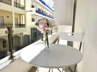 a white table with a vase of flowers on a balcony at Nutmeg - 50mtrs to beach - by HD PROPERTIES in Quarteira