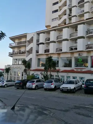 a parking lot in front of a large building at Apartamento Maria do Céu Villa Magna in Albufeira