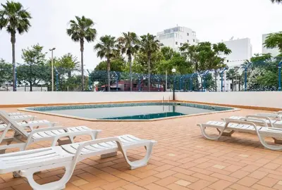 a swimming pool with white benches next to avisorvisor at Quarteira beach house in Quarteira