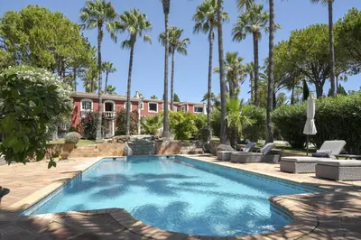 a swimming pool in front of a house with palm trees at Villa Oasis by CadenzaLux in Almancil