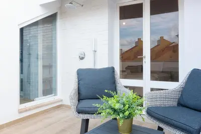 a porch with two chairs and a vase of flowers at CATCH - Vilamoura in Vilamoura