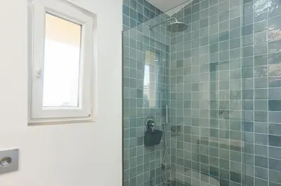 a bathroom with a shower with blue tiles at CATCH - Vilamoura in Vilamoura