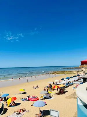 a group of people on a beach with umbrellas at On The BEACH Stunning Apartment Albufeira Olhos de Água in Albufeira