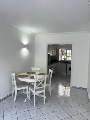 a white dining room with a table and chairs at Relaxing 2 Bedroom House 5 minutes away from Vilamoura Marina in Quarteira