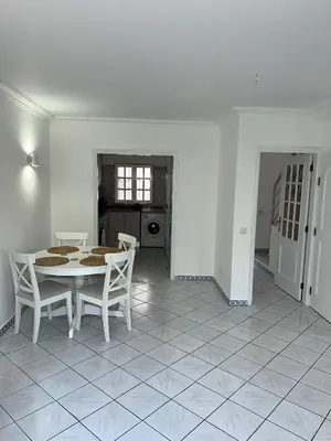 a white dining room with a table and chairs at Relaxing 2 Bedroom House 5 minutes away from Vilamoura Marina in Quarteira