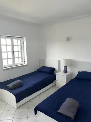 a white bedroom with two beds and a window at Relaxing 2 Bedroom House 5 minutes away from Vilamoura Marina in Quarteira