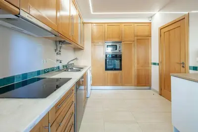 a kitchen with wooden cabinets and a sink and oven at Vilamoura Hideaway - Golf, Pool & Beach in Vilamoura