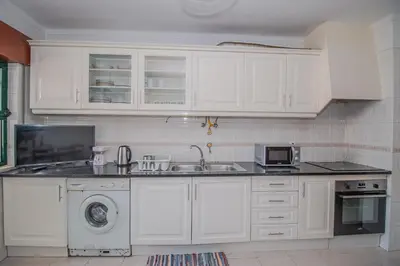 a kitchen with white cabinets and a sink at Charming Private Rooms in an Apartment A2 Penha - Faro in Faro