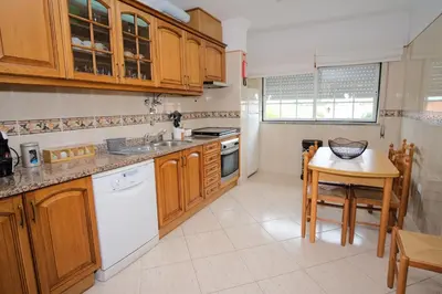 a kitchen with wooden cabinets and a table and a counter top at Apartamento T2 em condomínio fechado. in Albufeira