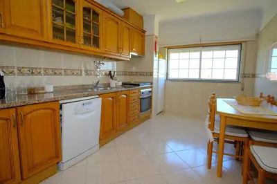 a kitchen with wooden cabinets and a white dishwasher at Apartamento T2 em condomínio fechado. in Albufeira