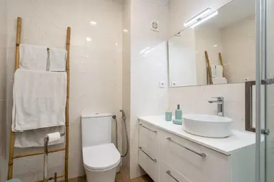 a white bathroom with a toilet and a sink at Beco do Sol, Albufeira in Albufeira