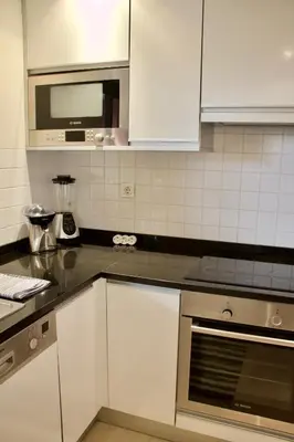 a kitchen with white cabinets and a microwave at Victoria Gardens Luxury Apartment by PA Hotels in Quarteira