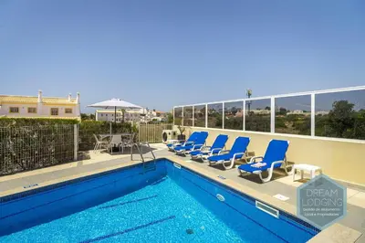 a swimming pool with blue lounge chairs on a balcony at Villa Rafaella 3 - Dream Lodging in Albufeira