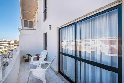 a balcony with two white chairs and a large window at Perfect location NEW holiday apartment in Albufeira
