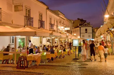 a group of people sitting at tables in a street at night at Perfect location NEW holiday apartment in Albufeira