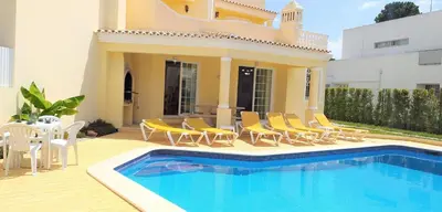 a villa with a swimming pool and chairs and a house at Vila Rosada in Quarteira