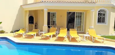 a group of yellow chairs sitting next to a pool at Vila Rosada in Quarteira