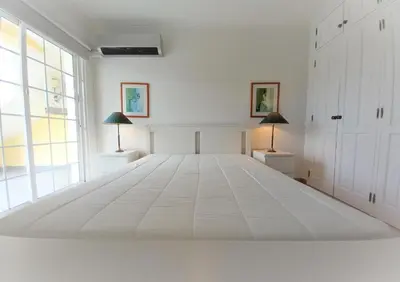 a large bed in a white room with two lamps at Vila Rosada in Quarteira