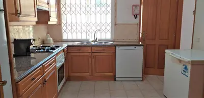 a kitchen with wooden cabinets and a sink and a window at Vila Rosada in Quarteira