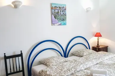 a bedroom with a bed with a blue and white headboard at Shiny Central Flat - Pool in Albufeira