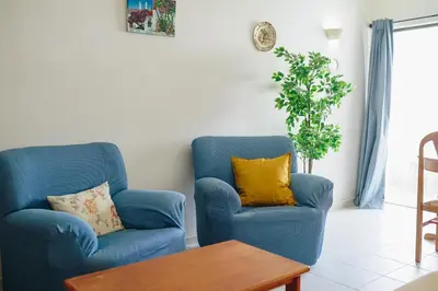a living room with two blue chairs and a table at Shiny Central Flat - Pool in Albufeira