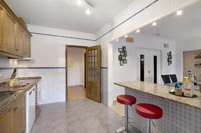 a kitchen with a counter and two red stools at Apartamento Manelito House by Sunyway in Albufeira