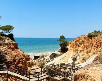 a staircase leading to a beach next to the ocean at Golden Blue Beach Falésia Apartment in Albufeira