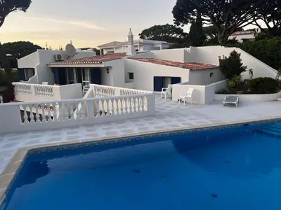 a patio with a table and umbrella next to a swimming pool at Royal Course Villa, Vale do Lobo in Vale do Lobo