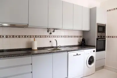 a white kitchen with a sink and a dishwasher at Apartamento Salgados Mar in Albufeira