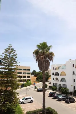 a parking lot with a palm tree and buildings at Apartamento Salgados Mar in Albufeira