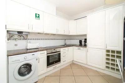 a white kitchen with a washer and dryer at Oura Sunrise 3F Apartment by Stay ici Algarve Holiday Rental in Albufeira