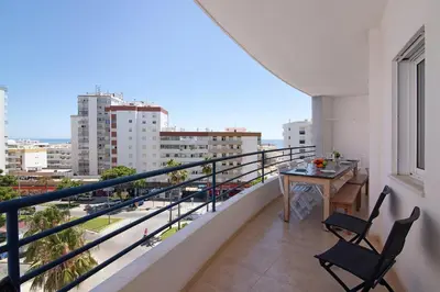 a balcony with a table and chairs and a view of the city at Quarteira Beach iii in Quarteira