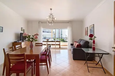 a dining room and living room with a table and a couch at Quarteira Beach ii in Quarteira