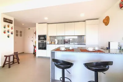 a kitchen with white cabinets and black stools at Marvell Design with heated pool&Playground in Albufeira