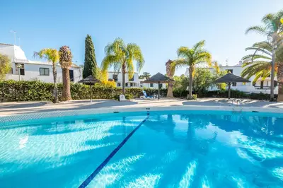 a swimming pool with palm trees and a building at Apartment São Rafael 63 - Beach - Pool - Free wi-fi - Air Con in Albufeira